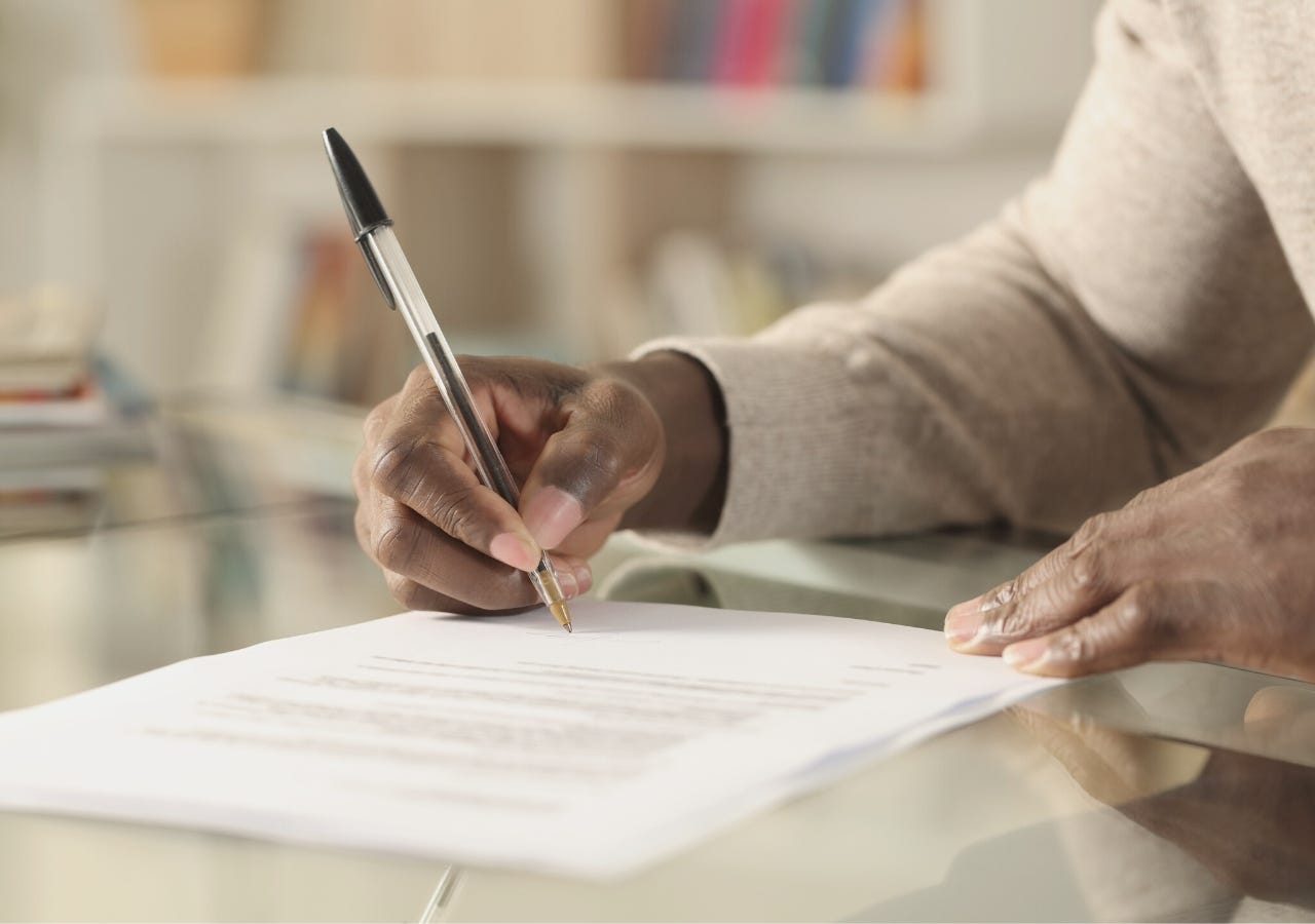 man signing a paper on a desk