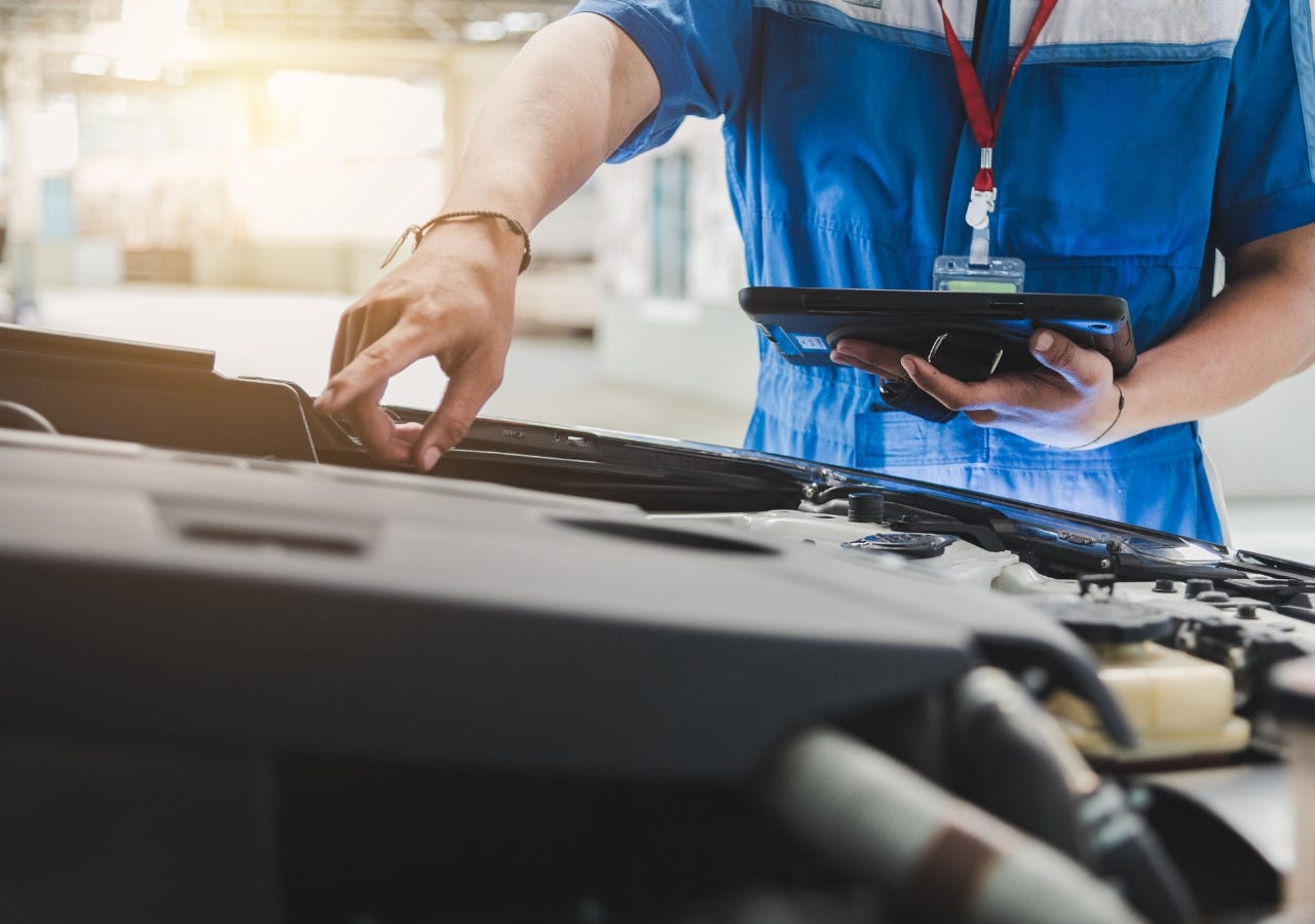 service technician pointing under the hood of a vehicle